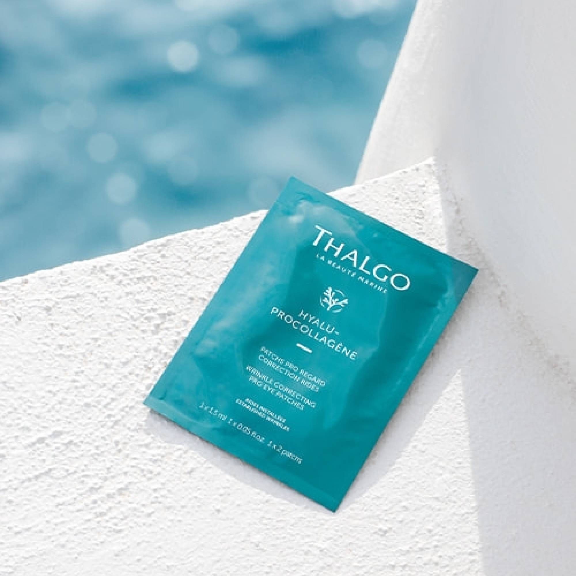 Türkisgrüne Einzelverpackung mit Produktnamen und Schriftzug. Enthält Augenpads. Auf weißer Oberfläche, Hintergrund Meer.