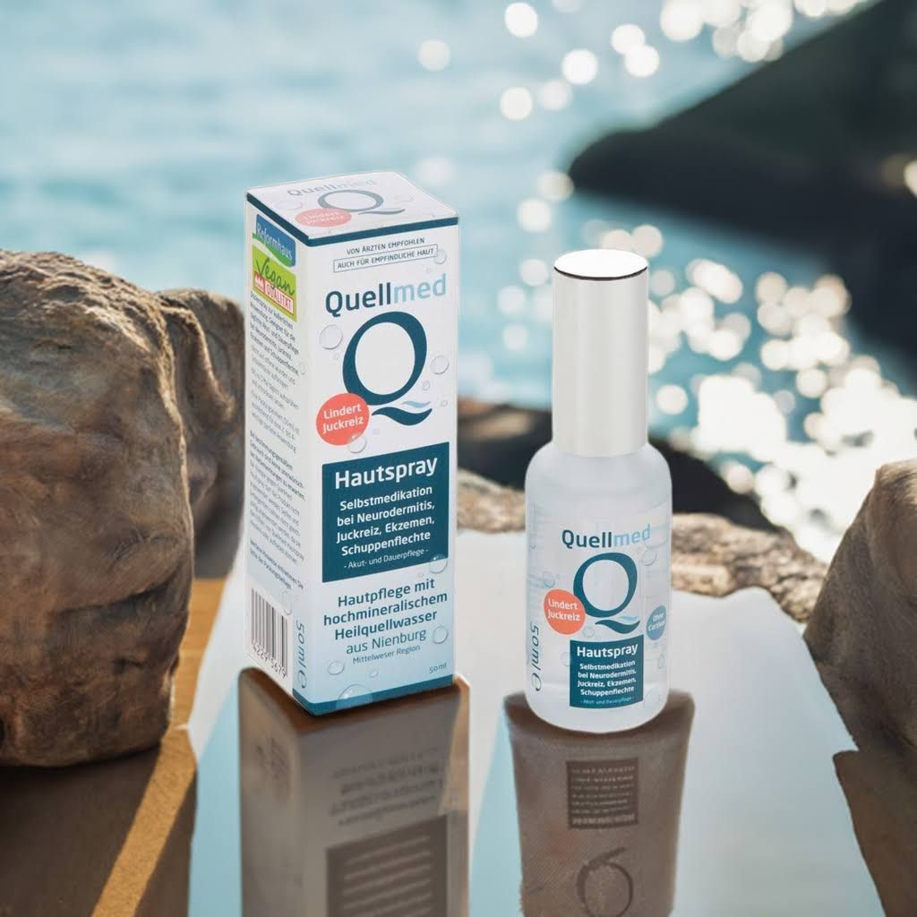 Spray-Flasche und Box von Quellmed. Aufschrift: Hautspray. Box mit Logo und Text. Hintergrund: Stein und Wasser.