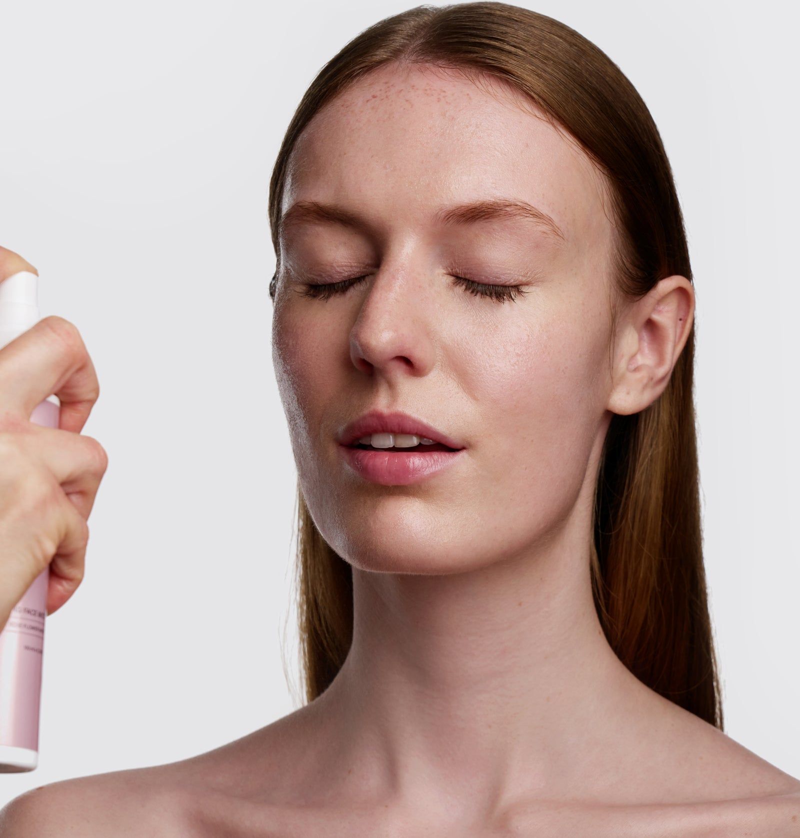 Frau mit geschlossenen Augen. Eine Hand sprüht Rosental Organics Hydrating Face Mist auf das Gesicht.