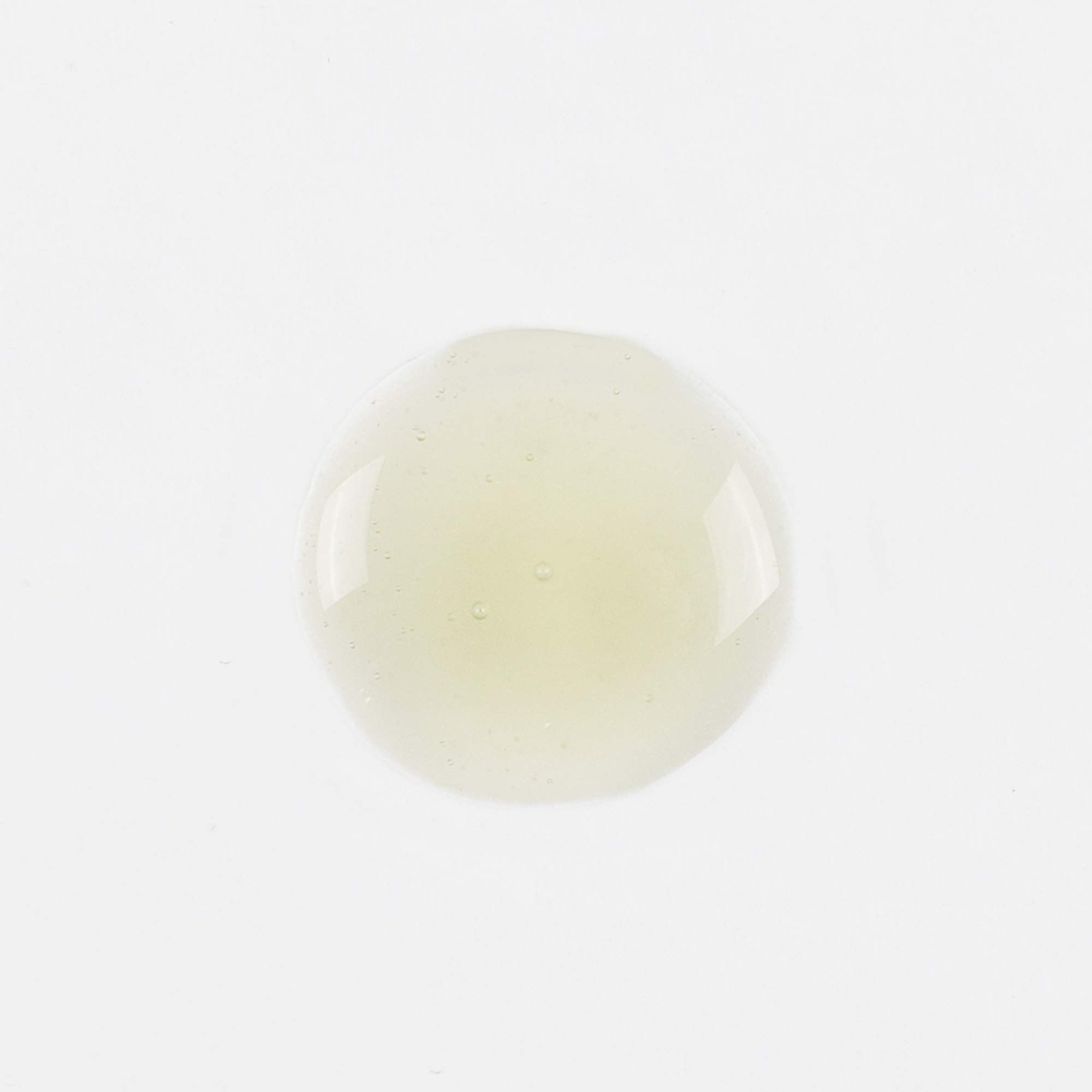 Klecks gelblicher Flüssigkeit auf weißem Hintergrund. Runde Form.