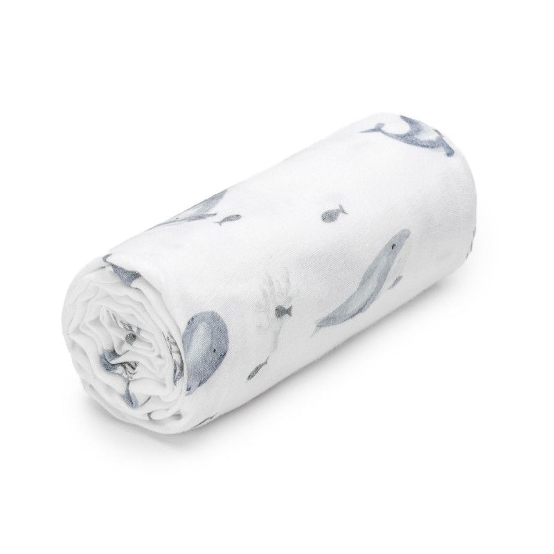 Gerolltes Musselinbadetuch mit Wal- und Fischmuster. Weißer Stoff mit grauen Illustrationen. Blick von oben.