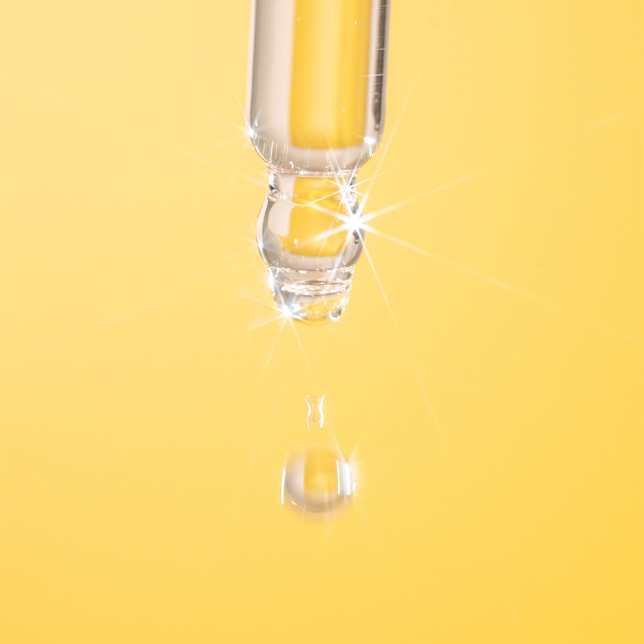 Nahaufnahme einer Pipette mit einer Tropfen Flüssigkeit. Gelber Hintergrund. Flüssigkeit tropft von der Pipette.