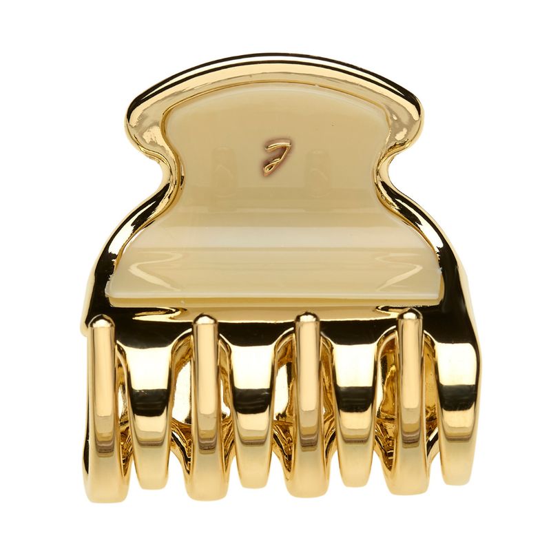 Haarspange aus goldfarbenem Metall mit cremefarbenem Einsatz. Sie hat eine geschwungene Form und mehrere Zähne.