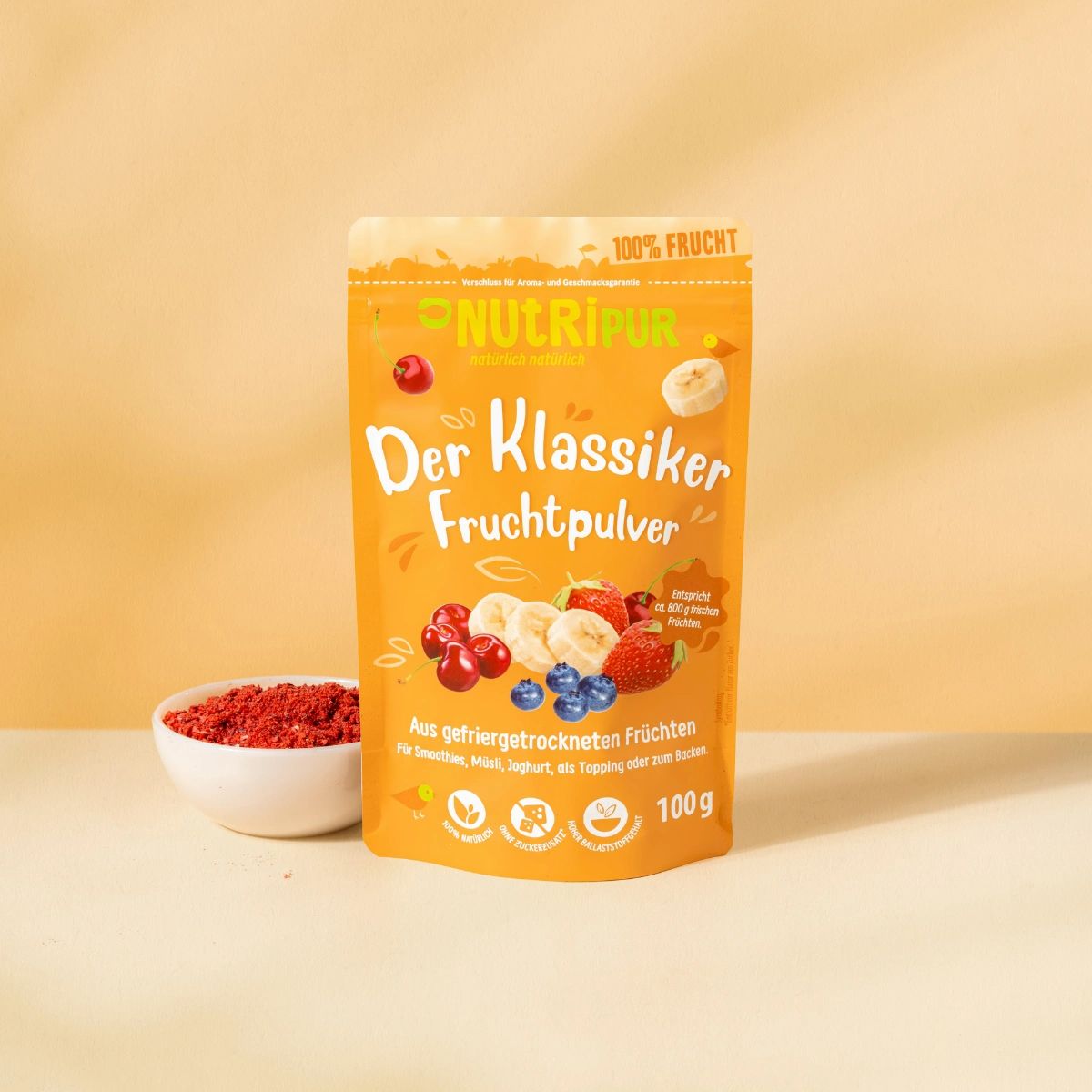 Orangefarbene Verpackung mit Fruchtpulver. Aufschrift: NutriPur, Der Klassiker Fruchtpulver. Daneben eine Schale mit rotem Pulver.