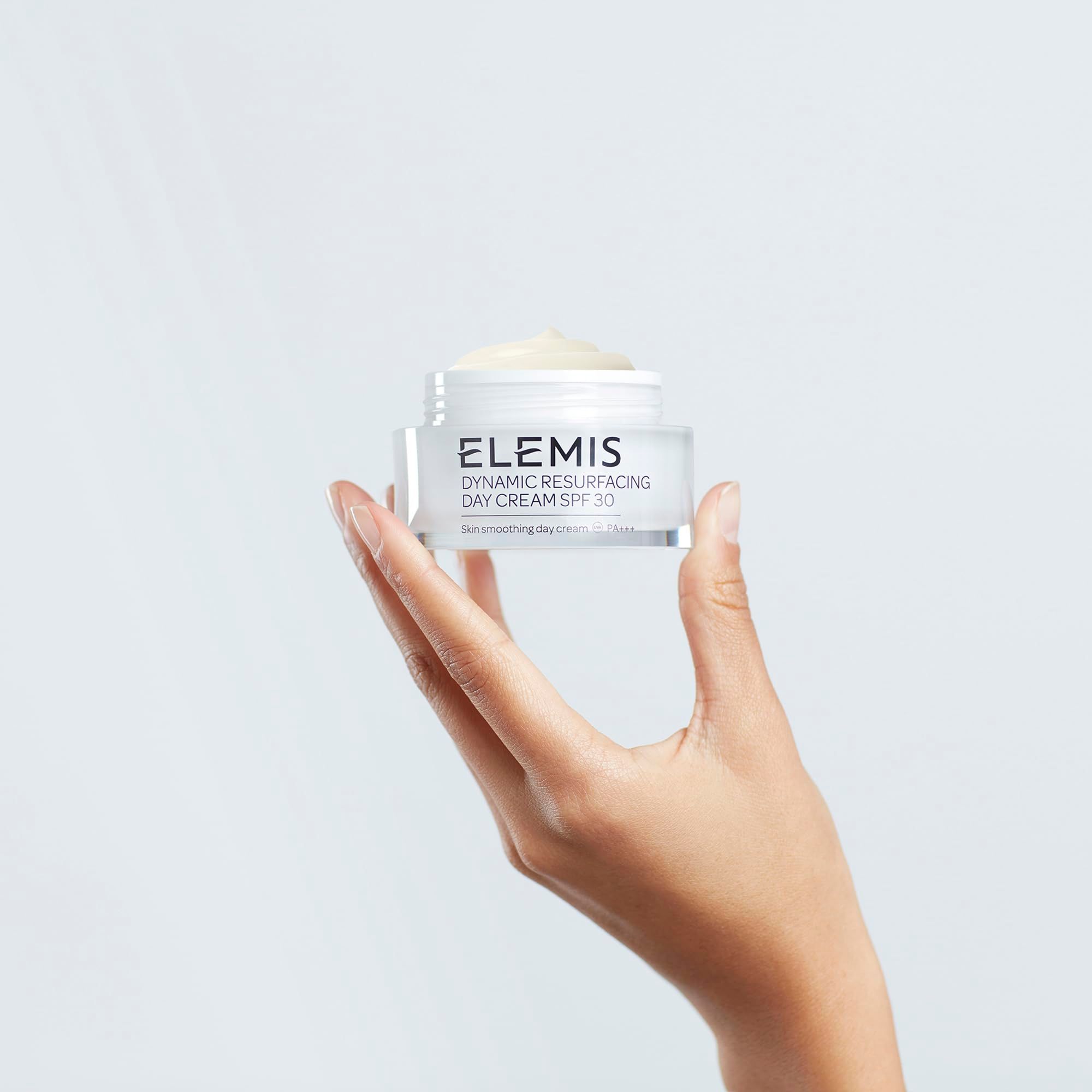 Hand hält einen geöffneten Cremebehälter. Aufschrift: Elemis Dynamic Resurfacing Day Cream SPF 30. Creme sichtbar.