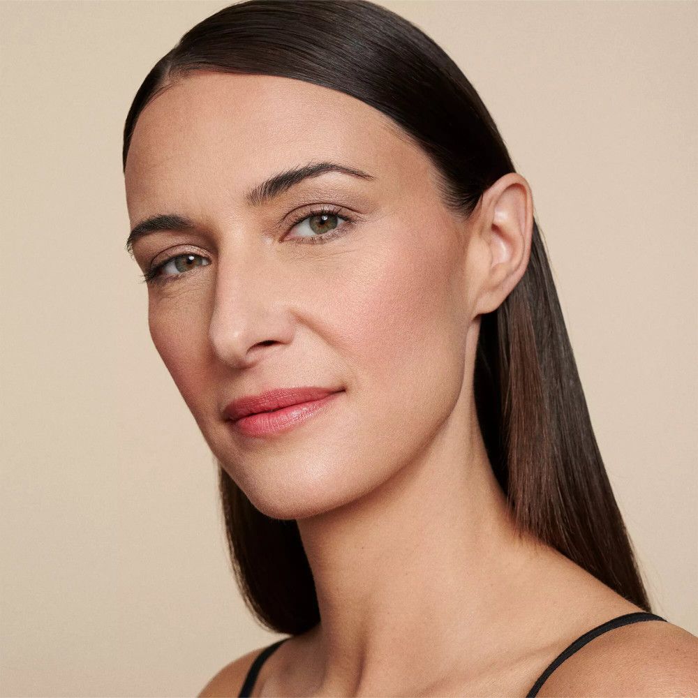 Porträt einer Frau mit langen, dunklen Haaren. Sie trägt Make-up, einschließlich Lidschatten und Lippenstift.