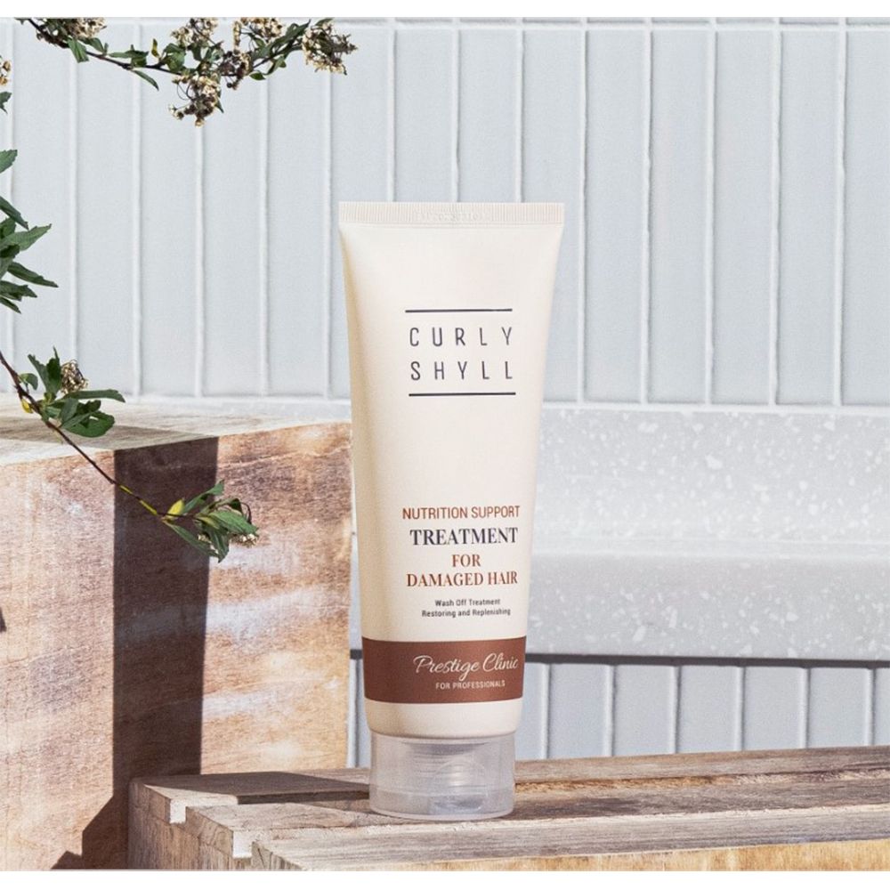 Beige Tube mit Schriftzug. Aufschrift: CURLY SHYLL, Nutrition Support Treatment for Damaged Hair, Prestige Clinic.