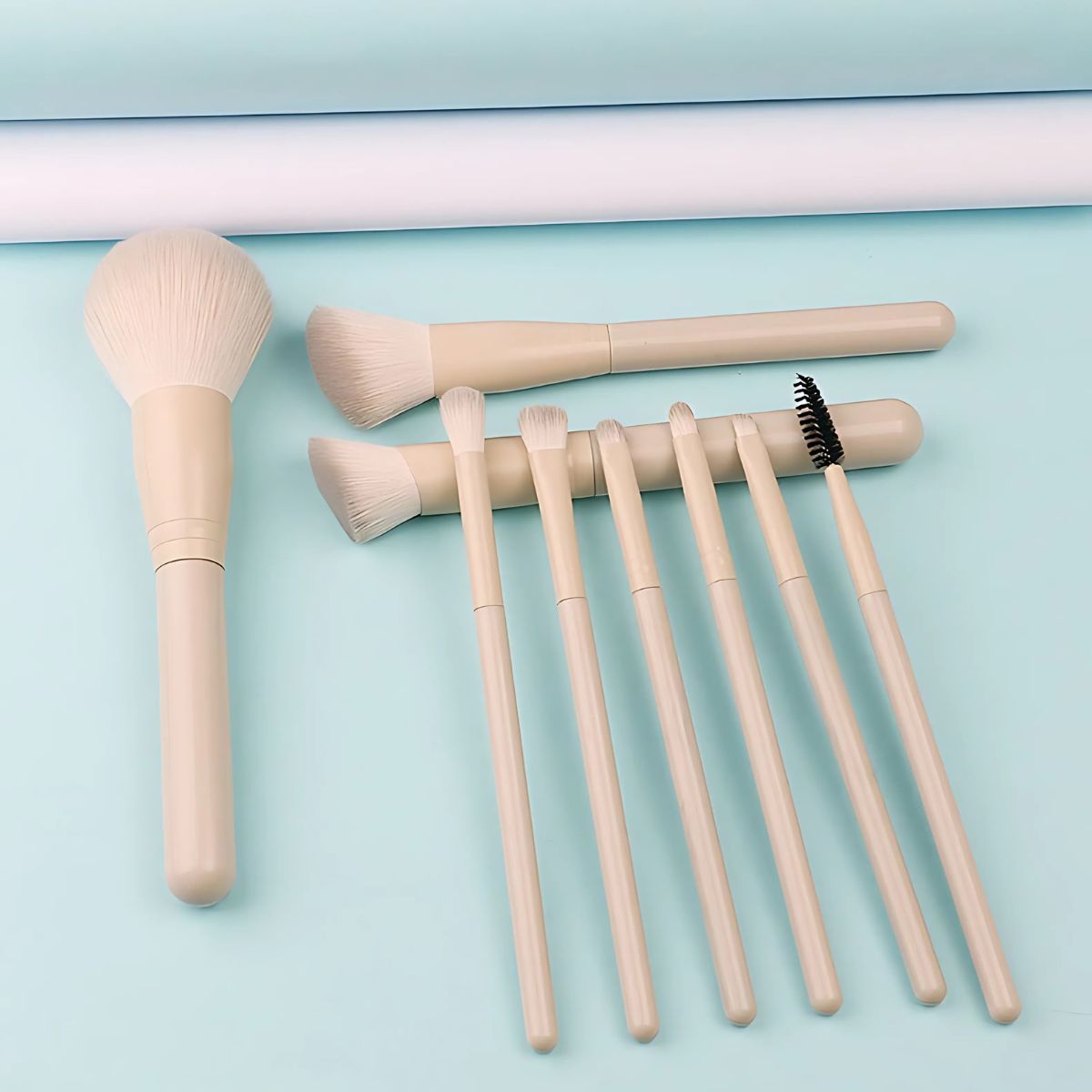 Ein Set aus acht hellbeigen Make-up-Pinseln mit unterschiedlichen Köpfen, darunter ein großer Puderpinsel und kleinere für Augen und Lippen.