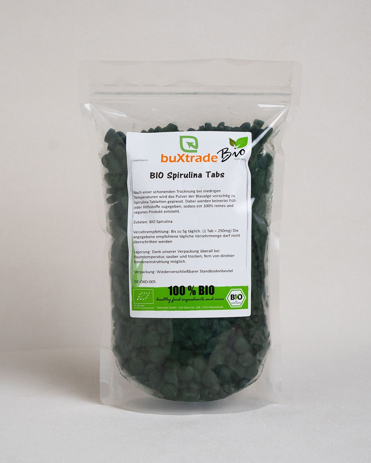 Transparente Plastiktüte mit dunkelgrünen Tabletten. Aufschrift: buXtrade Bio Spirulina Tabs. Bio-Siegel. Text in deutscher Sprache.