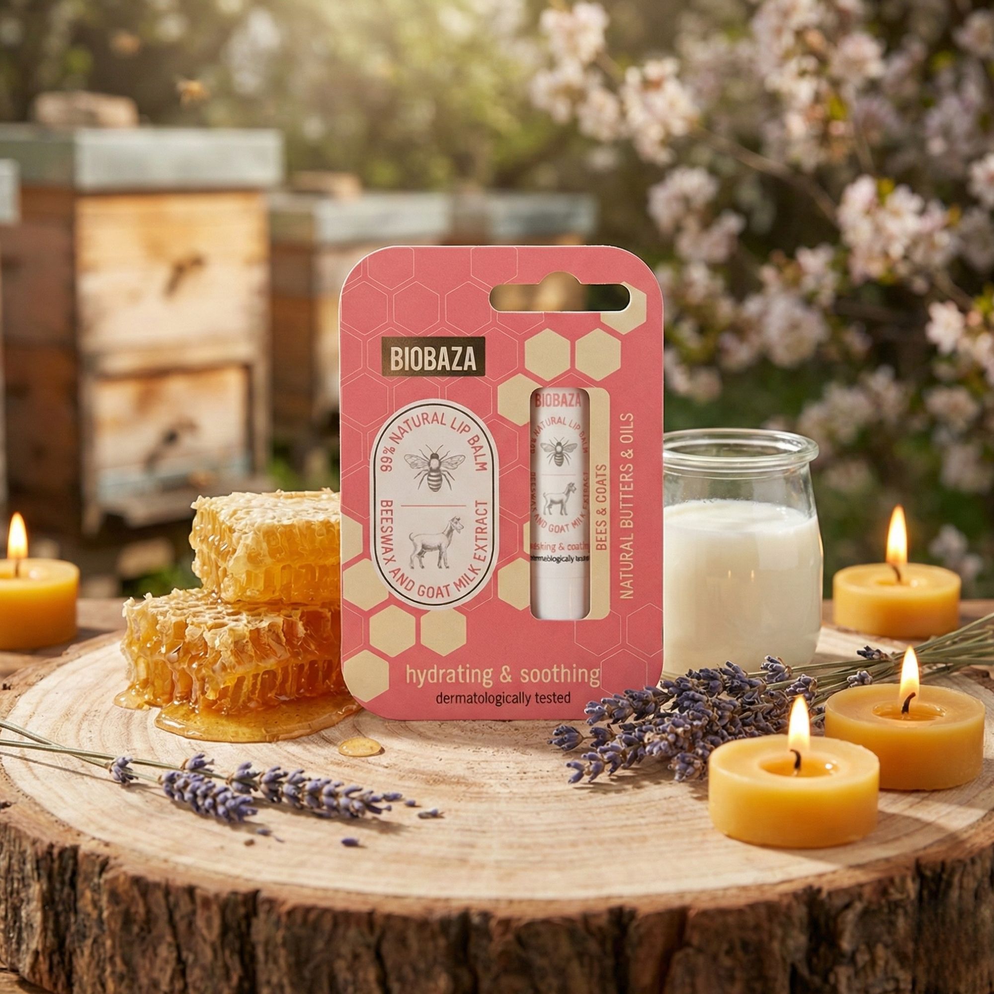 Lippenbalsam-Verpackung mit Honigwaben, Kerzen und Blumen. Aufschrift: Biobaza. Im Hintergrund: Bienenstöcke. Produkt: Lippenbalsam-Stift.