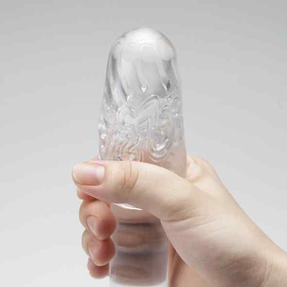 Transparentes, längliches Produkt mit Reliefmuster, gehalten von einer Hand. Auf hellem Hintergrund.