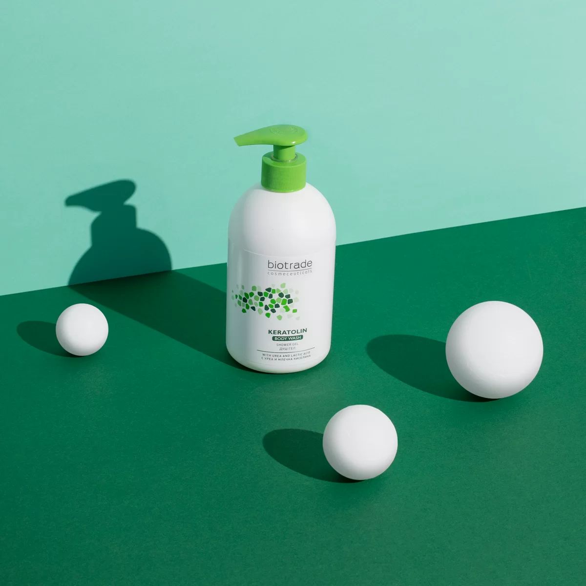 Weißer Spender mit grünem Pumpkopf. Aufschrift Biotrade Keratolin. Drei weiße Kugeln liegen auf grünem Hintergrund.