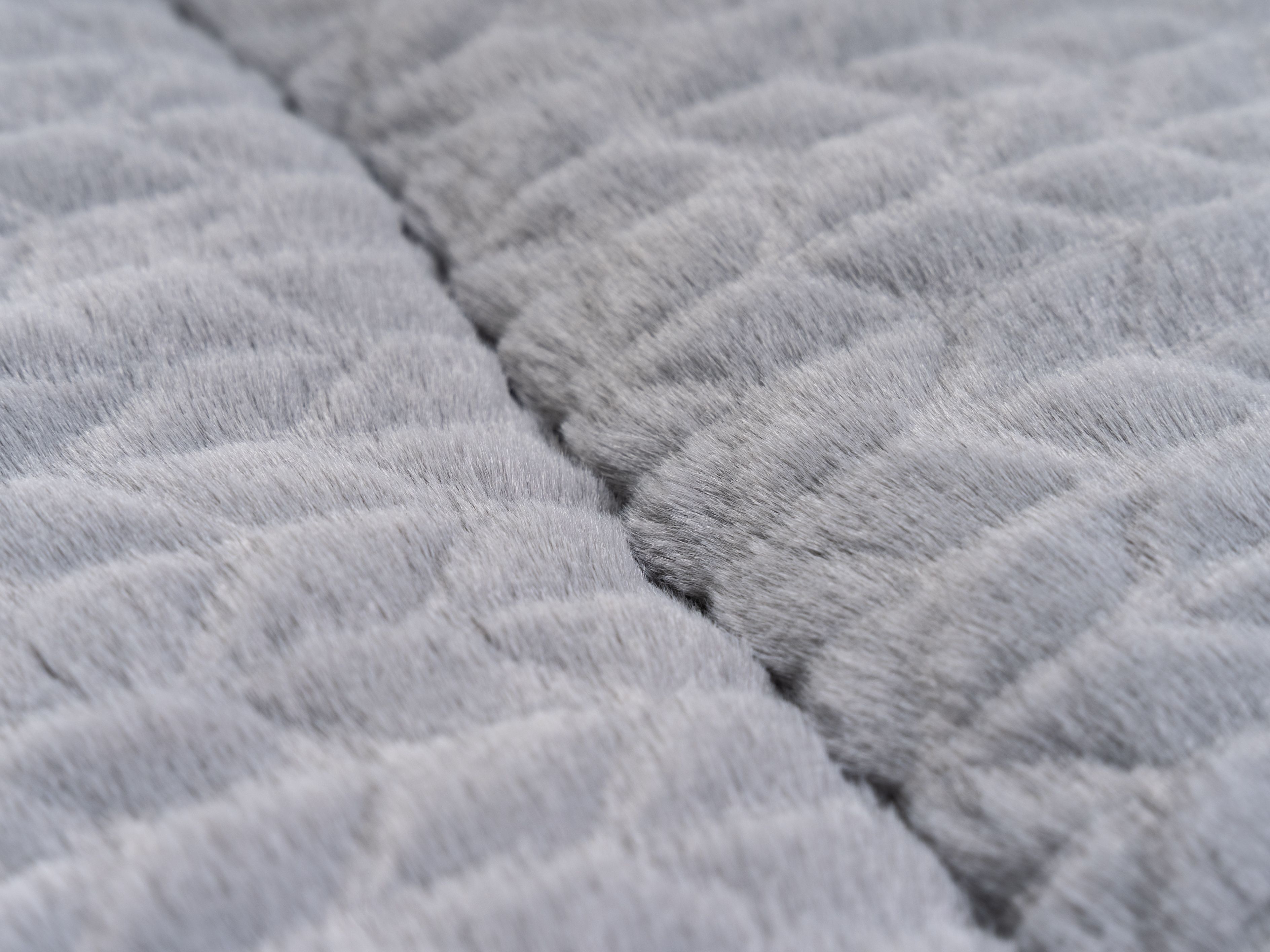 Nahaufnahme der strukturierten Oberfläche einer grauen Liegedecke. Die Struktur ist rautenförmig.