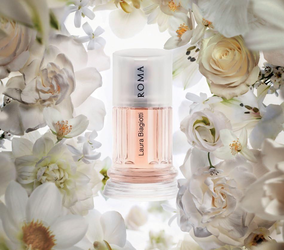 Parfümflakon umgeben von weißen Blüten. Rosa Flüssigkeit, zylindrische Form, klarer Deckel, Schriftzug ROMA.