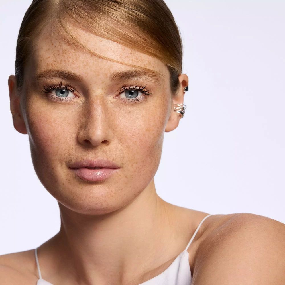 Porträt einer Frau mit blonden Haaren und Sommersprossen. Ohrringe und Hautton deutlich erkennbar.