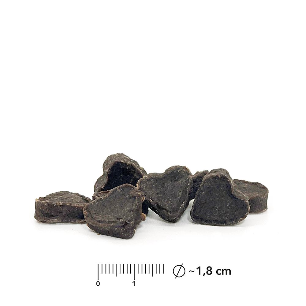 Herzförmige, dunkle Snacks. Durchmesser ca. 1,8 cm. Auf weißem Hintergrund.