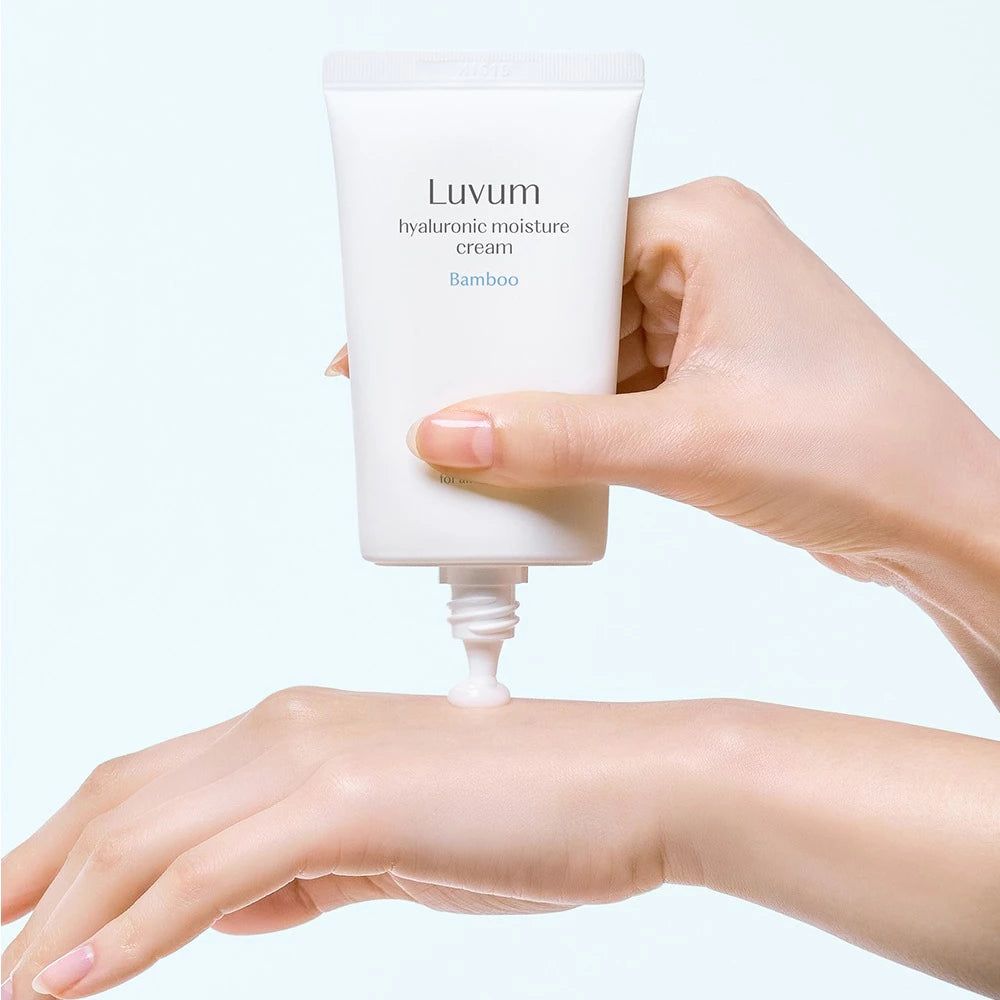 Hand drückt Creme aus weißer Tube. Aufschrift: LUVUM, Hyaluronsäure Feuchtigkeitscreme, Bambus. Creme auf Hand aufgetragen.