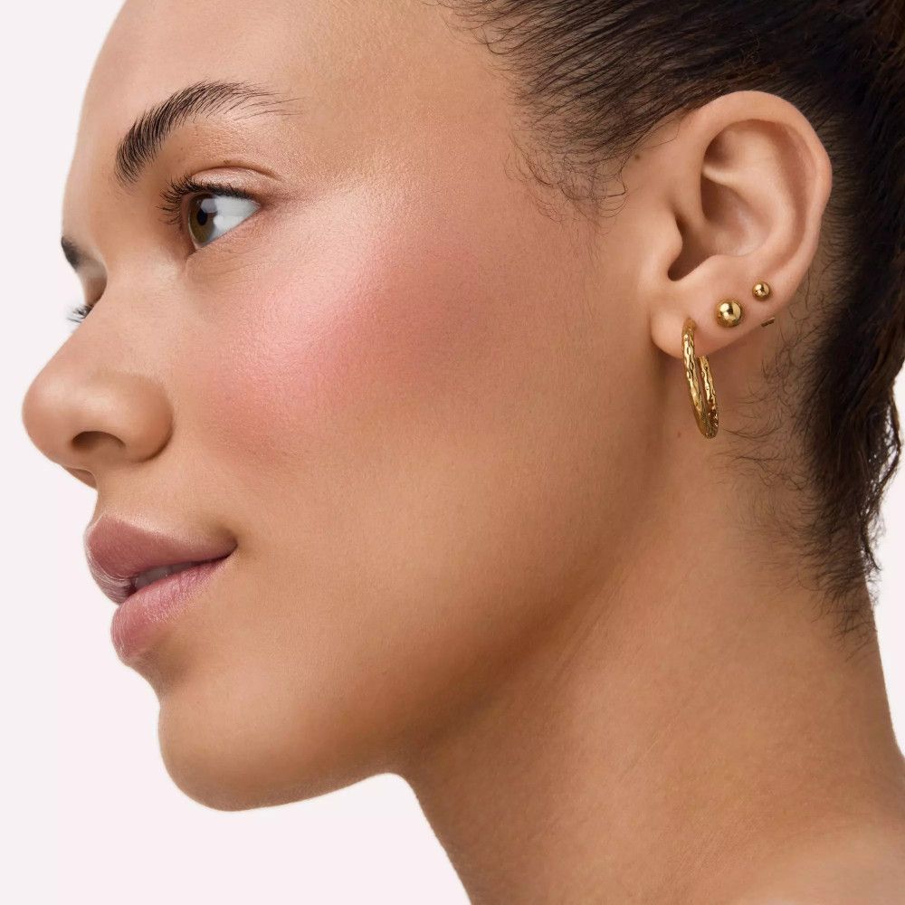 Porträt einer Frau mit Rouge auf den Wangen. Goldene Ohrringe. Blick zur Seite.