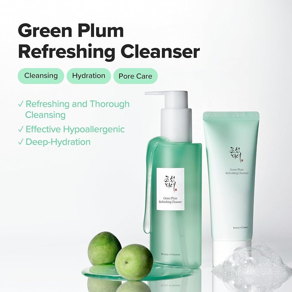 Grüner Spender und Tube neben grünen Pflaumen. Text: Green Plum Refreshing Cleanser. Schaum. Auf weißem Hintergrund.