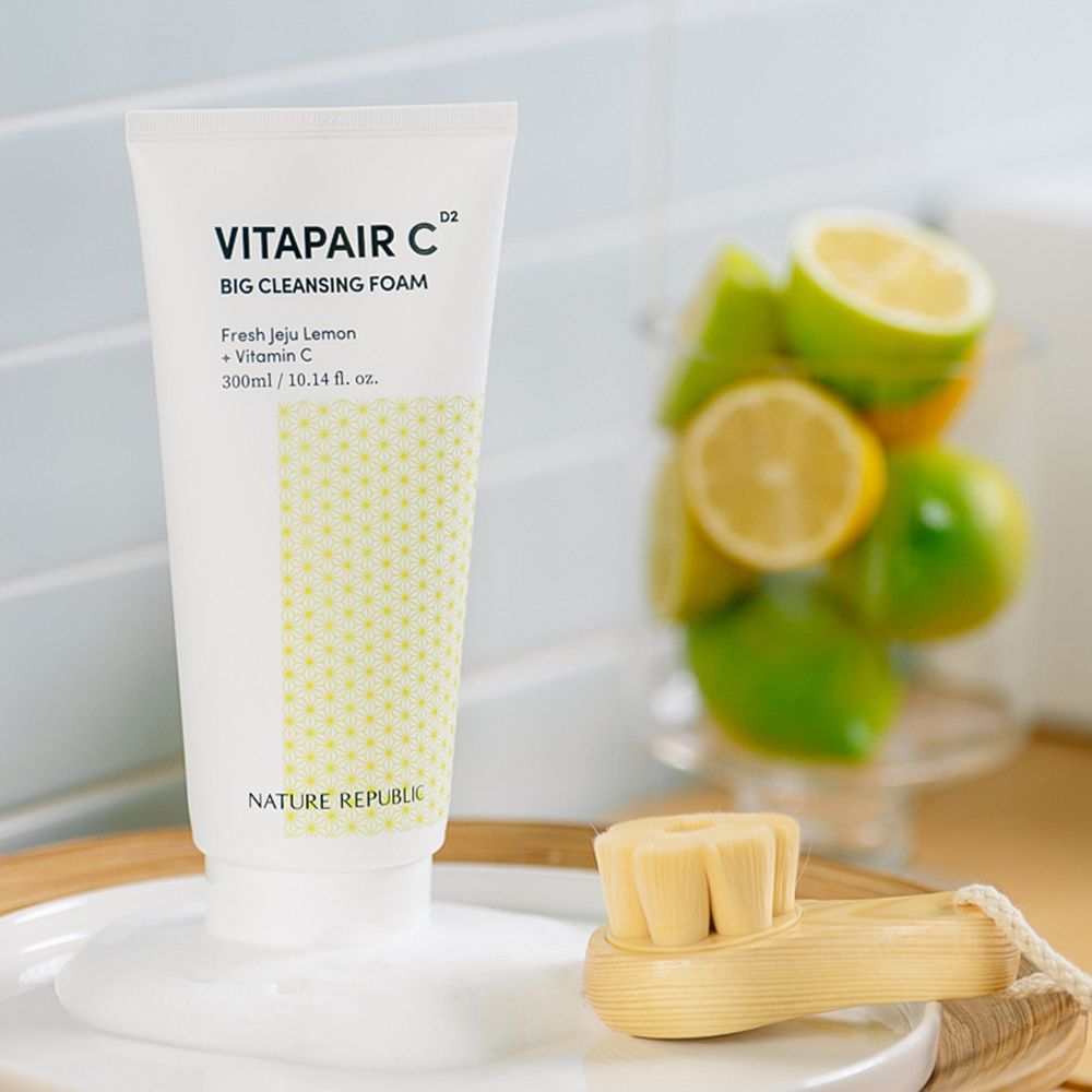 Weißer Tubenreiniger mit gelbem Muster. Aufschrift: Vitapair C Big Cleansing Foam, Nature Republic. Daneben Zitronen und eine Bürste.