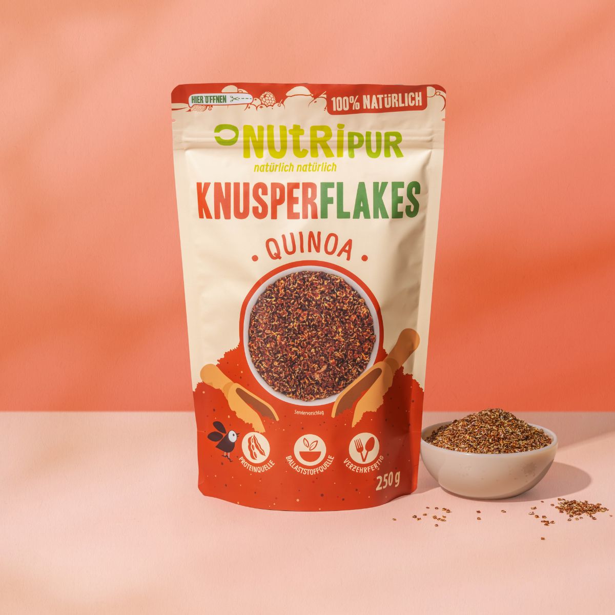 Beutel mit NutriPur Knusperflakes Quinoa. Aufdruck: 100% natürlich, 250g. Abbildung von Flakes in Schüssel.