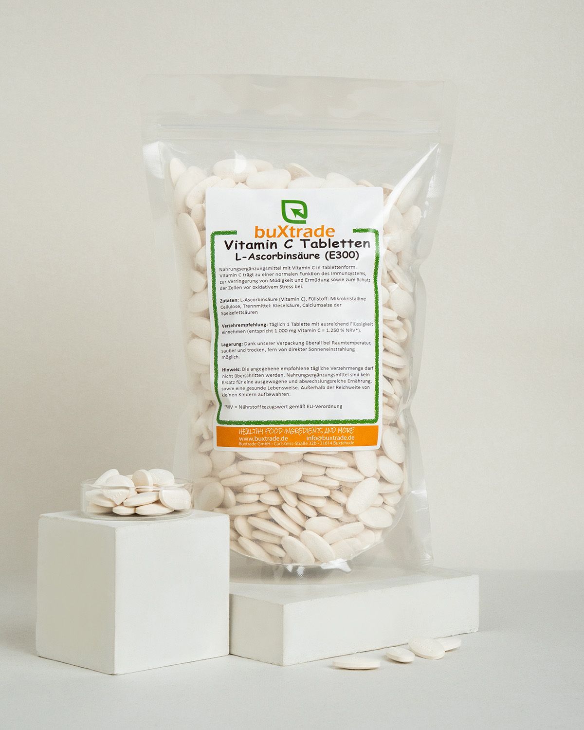 buXtrade Vitamin C Tabletten in einem Beutel, daneben ein kleiner Würfel mit Tabletten. Weiße, ovale Tabletten.