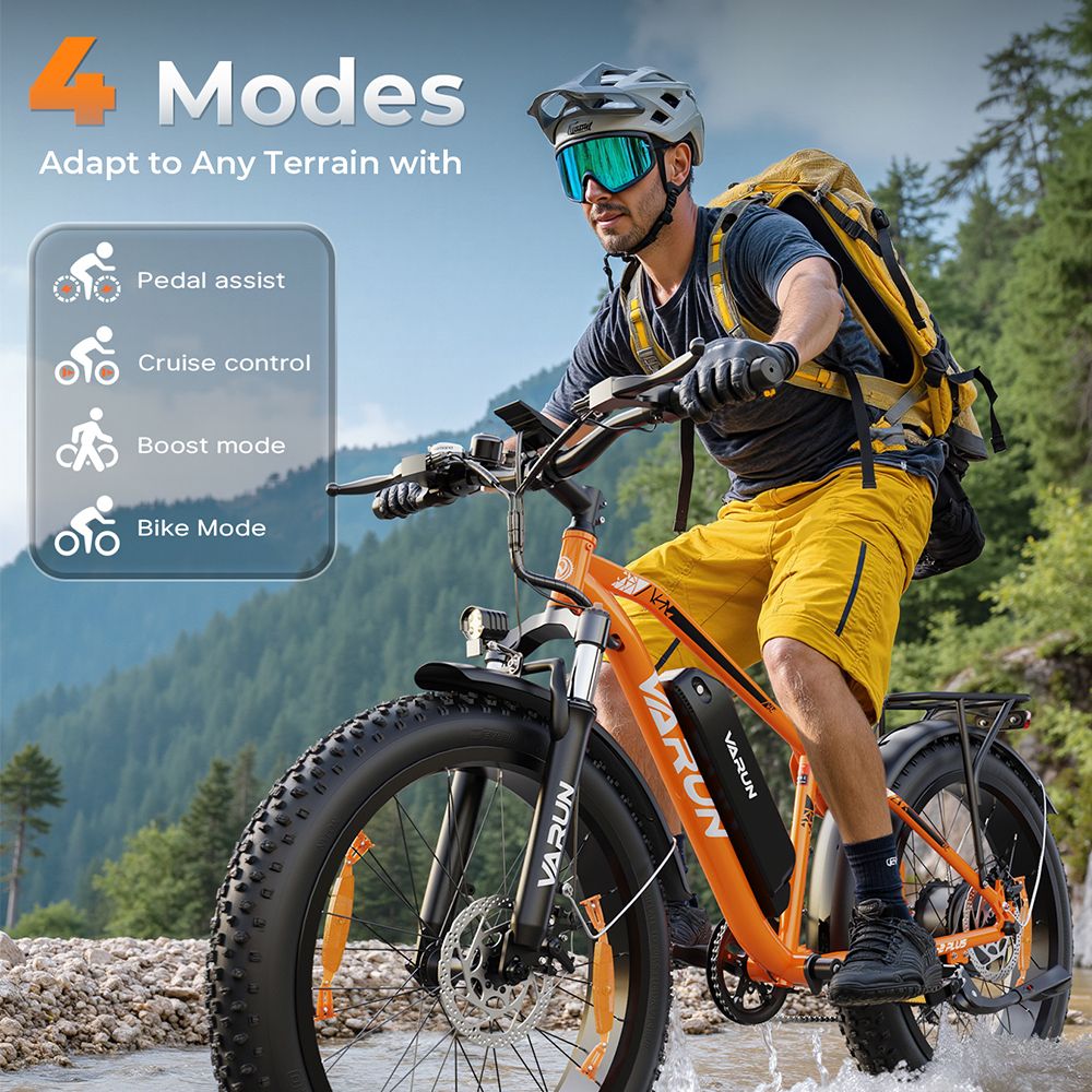Mann fährt auf einem orangefarbenen VARUN E-Mountainbike durch einen Bach. 4 Fahrmodi. Helm, Rucksack, Brille.