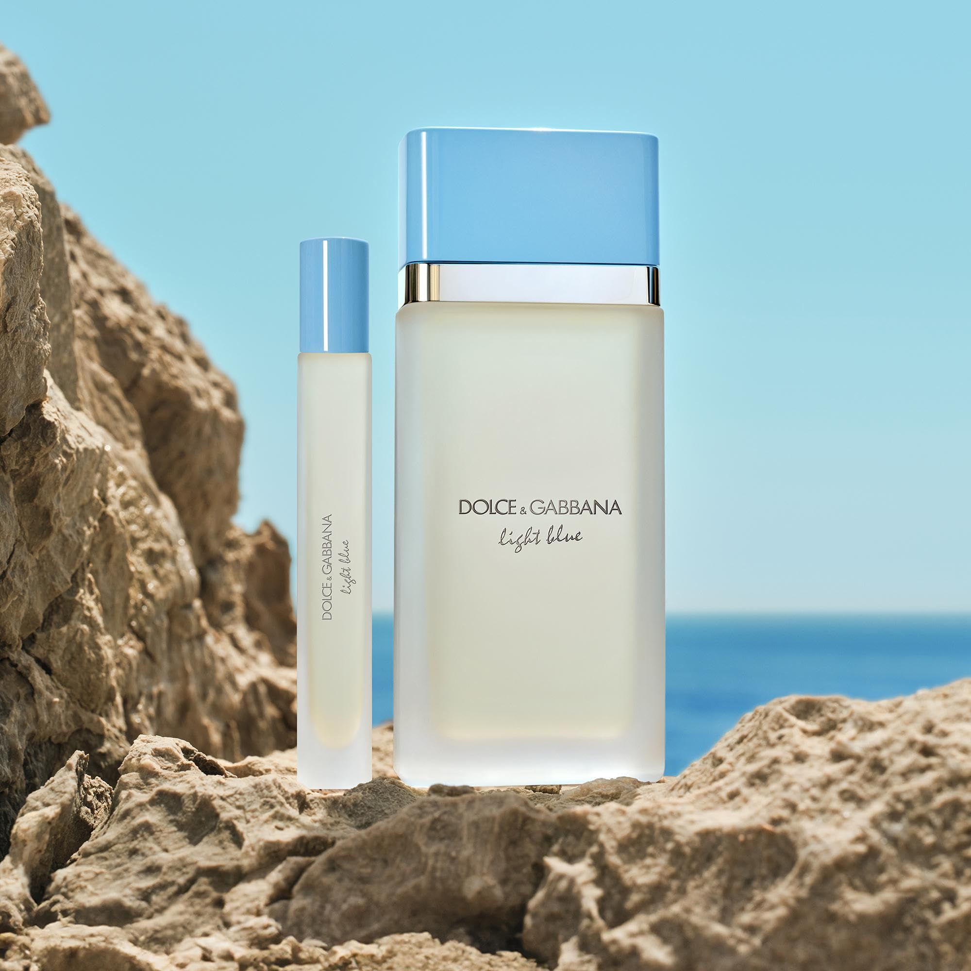 Rechteckiger Flakon und kleinerer Flakon mit hellblauem Deckel auf Felsen vor blauem Meer. Aufschrift: Dolce & Gabbana Light Blue.