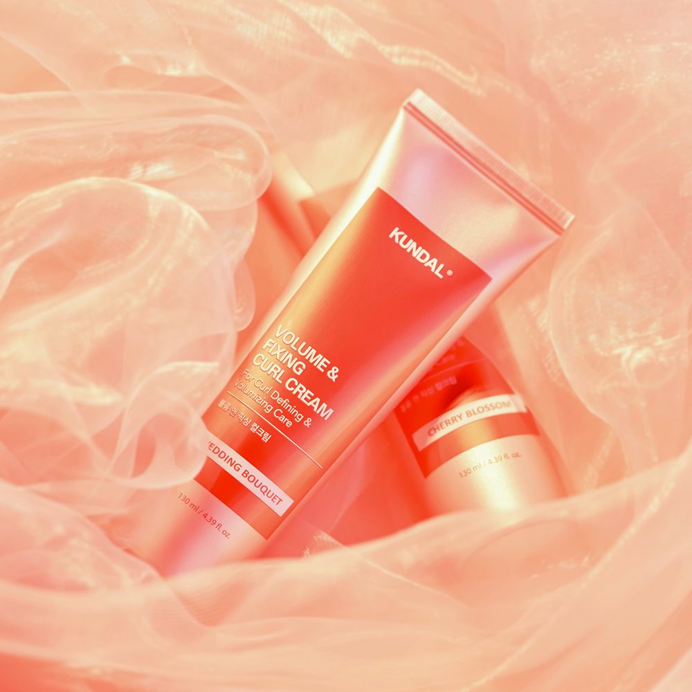 Lockencreme-Tube, rot-weiß, KUNDAL-Logo, Text: Volume & Fixing Curl Cream, Wedding Bouquet. Im rosa Stoff drapiert.