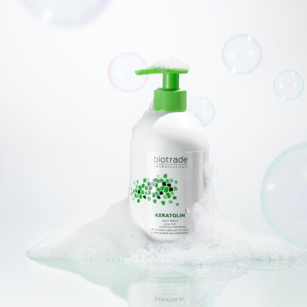 Weißer Spender mit grünem Pumpkopf in Schaum. Aufschrift Biotrade Keratolin. Seifenblasen im Hintergrund.