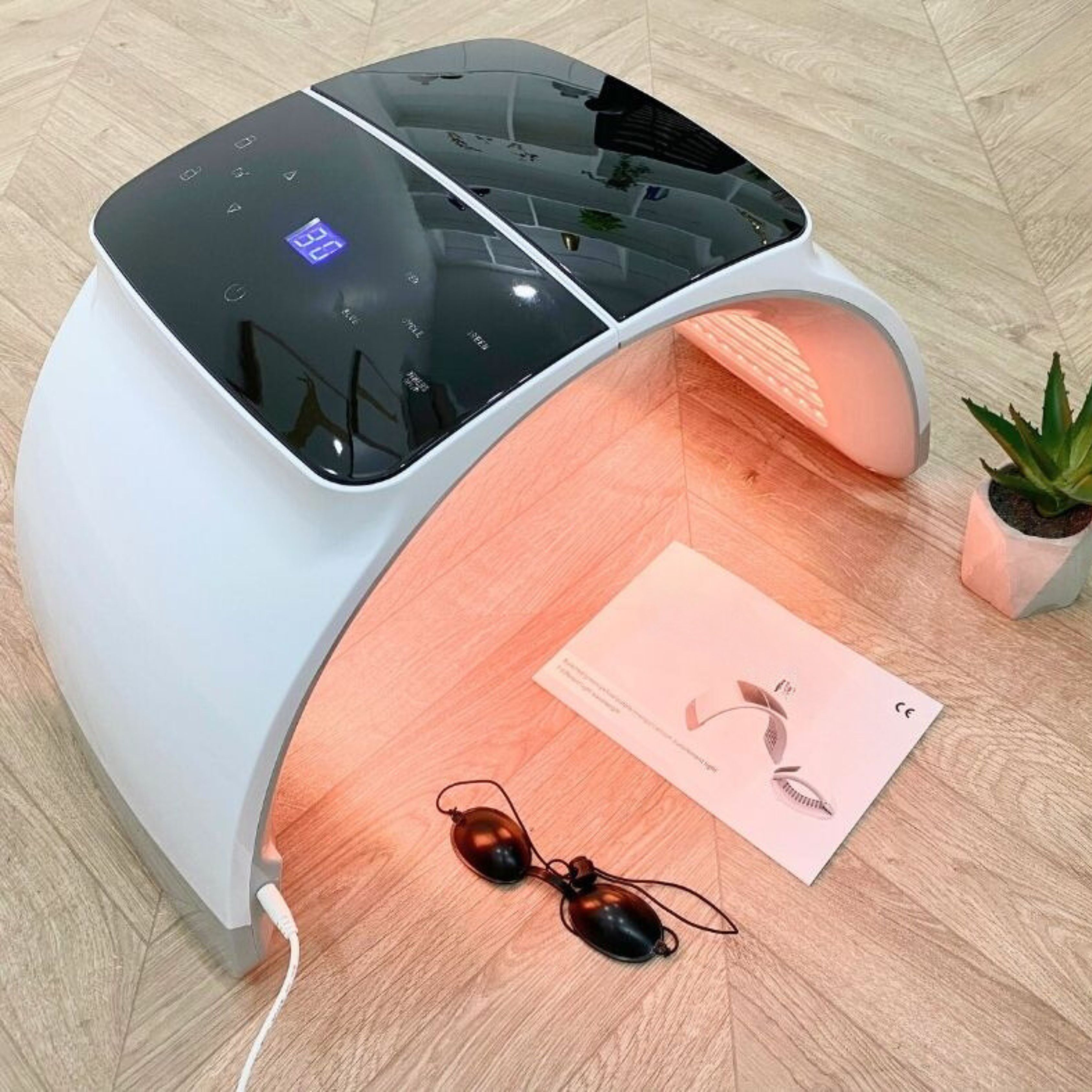 Gesichts-Spa mit LED-Technologie. Weißes Gerät, rotes Licht. Bedienfeld. Schutzbrille und Anleitung.