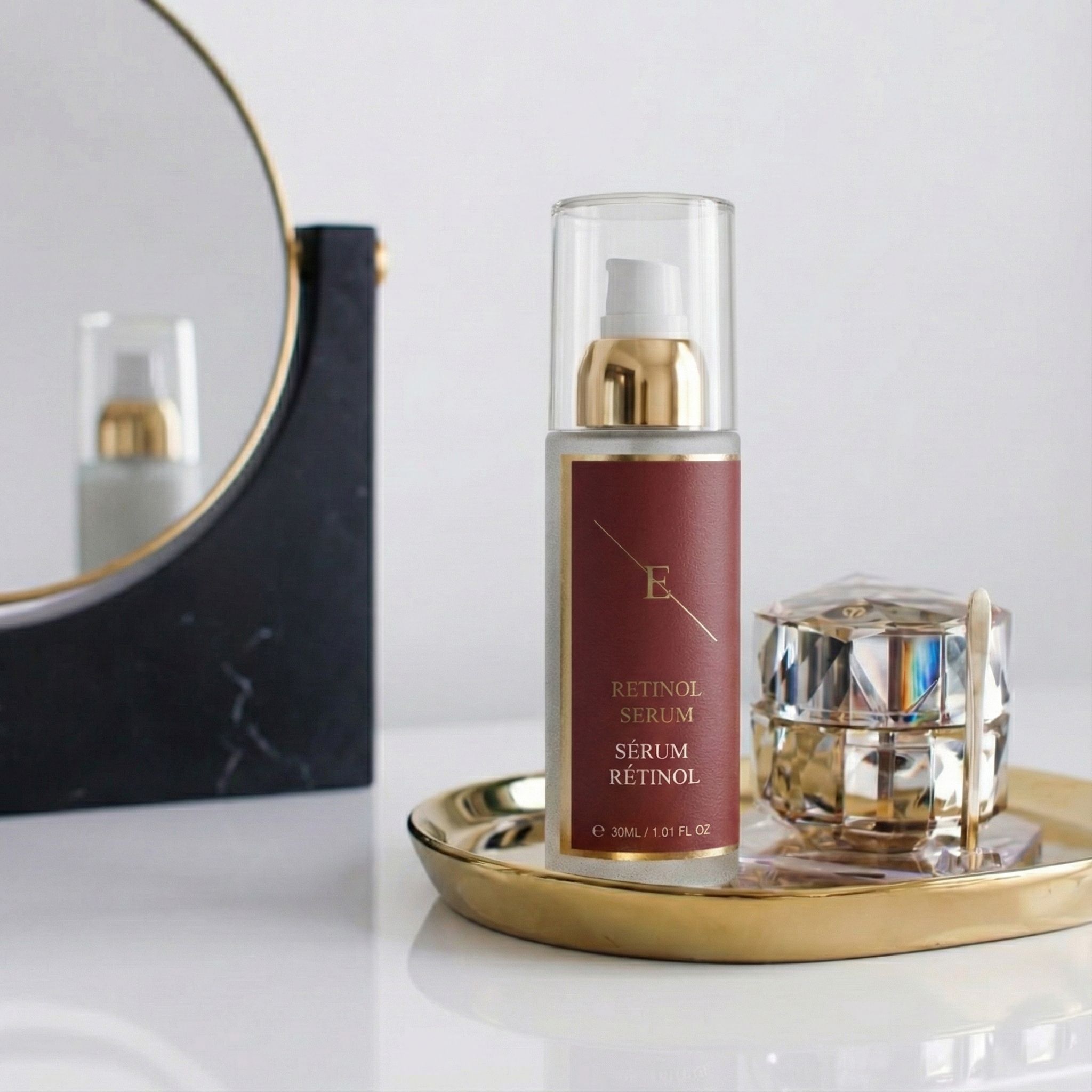 Serumflasche auf goldener Schale, neben Schmuckdose und Spiegel. Rotes Etikett mit Text: Retinol Serum, Sérum Rétinol.
