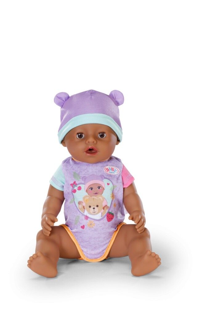 BABY born Puppe mit lila Mütze und Strampler. Puppe sitzt. Hautfarbe: braun.