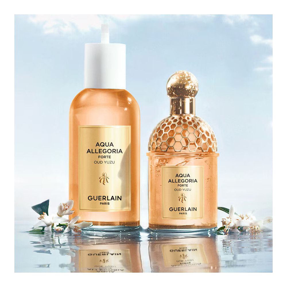 Zwei Flakons. Rechts: Goldfarbenes Wabenmuster. Links: Weißer Verschluss. Goldfarbene Etiketten. Text: AQUA ALLEGORIA FORTE OUD YUZU, Guerlain.