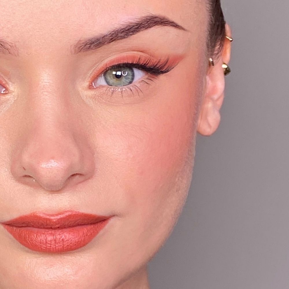 Nahaufnahme eines Gesichts mit geschminkten Augen, Wangen und Lippen. Lippenstift in Korallenrot. Hautton: hell.