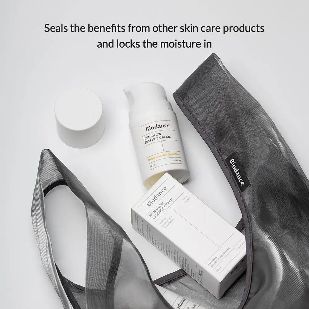 Produktflasche und Verpackung in einer Netztasche. Text: Biodance Skin-Glow Essence Cream. Versiegelt Vorteile.
