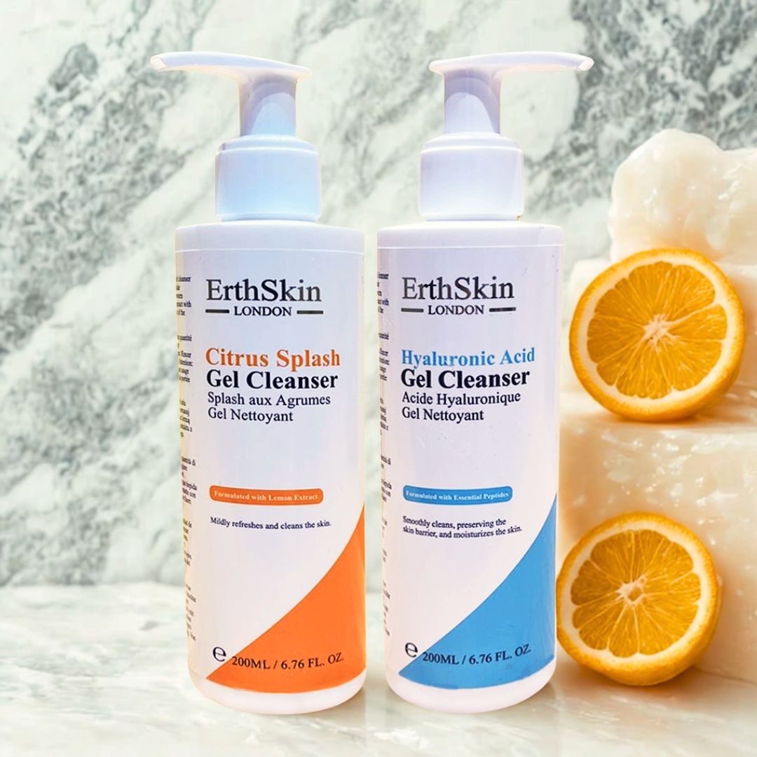 Zwei ErthSkin London Gel-Reiniger-Flaschen. Orangefarbene Flasche mit "Citrus Splash", blaue mit "Hyaluronsäure". Orangenstücke daneben.