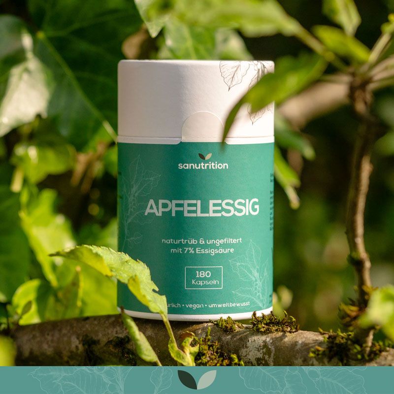 Sanutrition Apfelessig-Kapseln in einer Dose, umgeben von grünen Blättern und Zweigen.