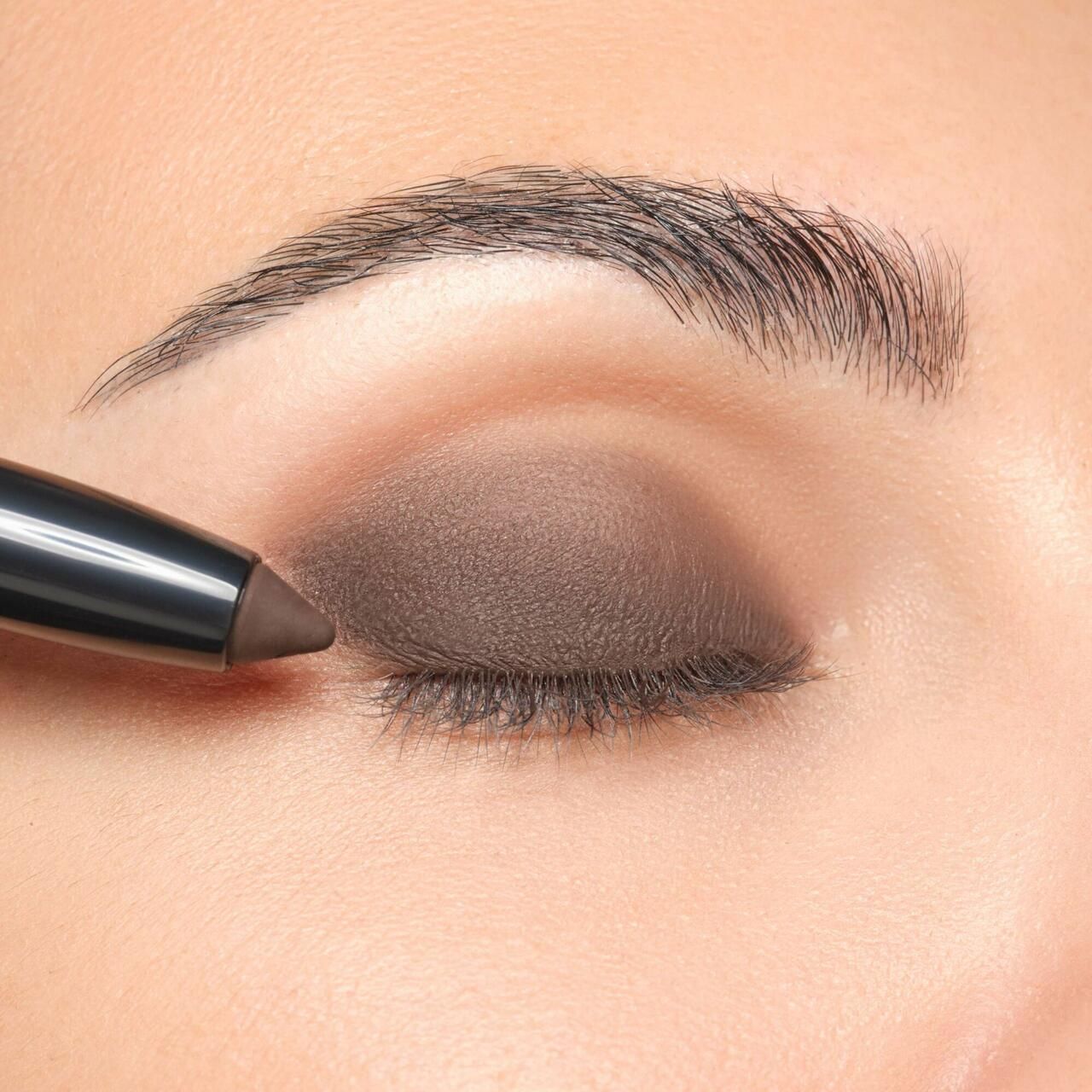 Auge mit braunem Lidschatten. Ein Eyeshadow Stylo wird aufgetragen.