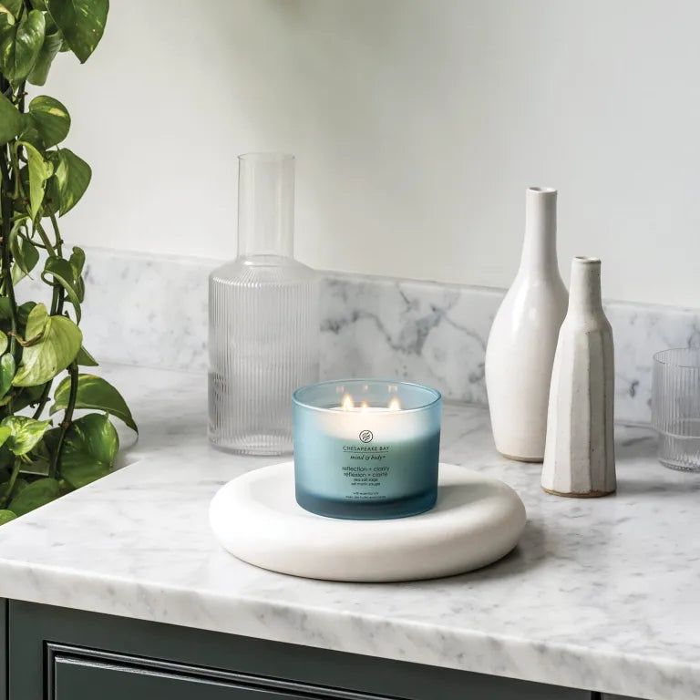 Blaue Kerze Chesapeake Bay, mind & body, reflection + clarity, auf weißem Podest. Dekoration mit Vasen.