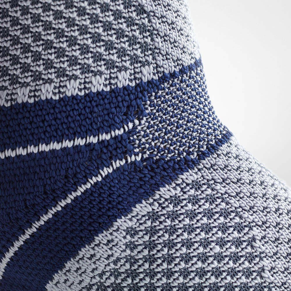 Nahaufnahme der Knöchelbandage, grau-blaues Strickmuster. Ohne Text.