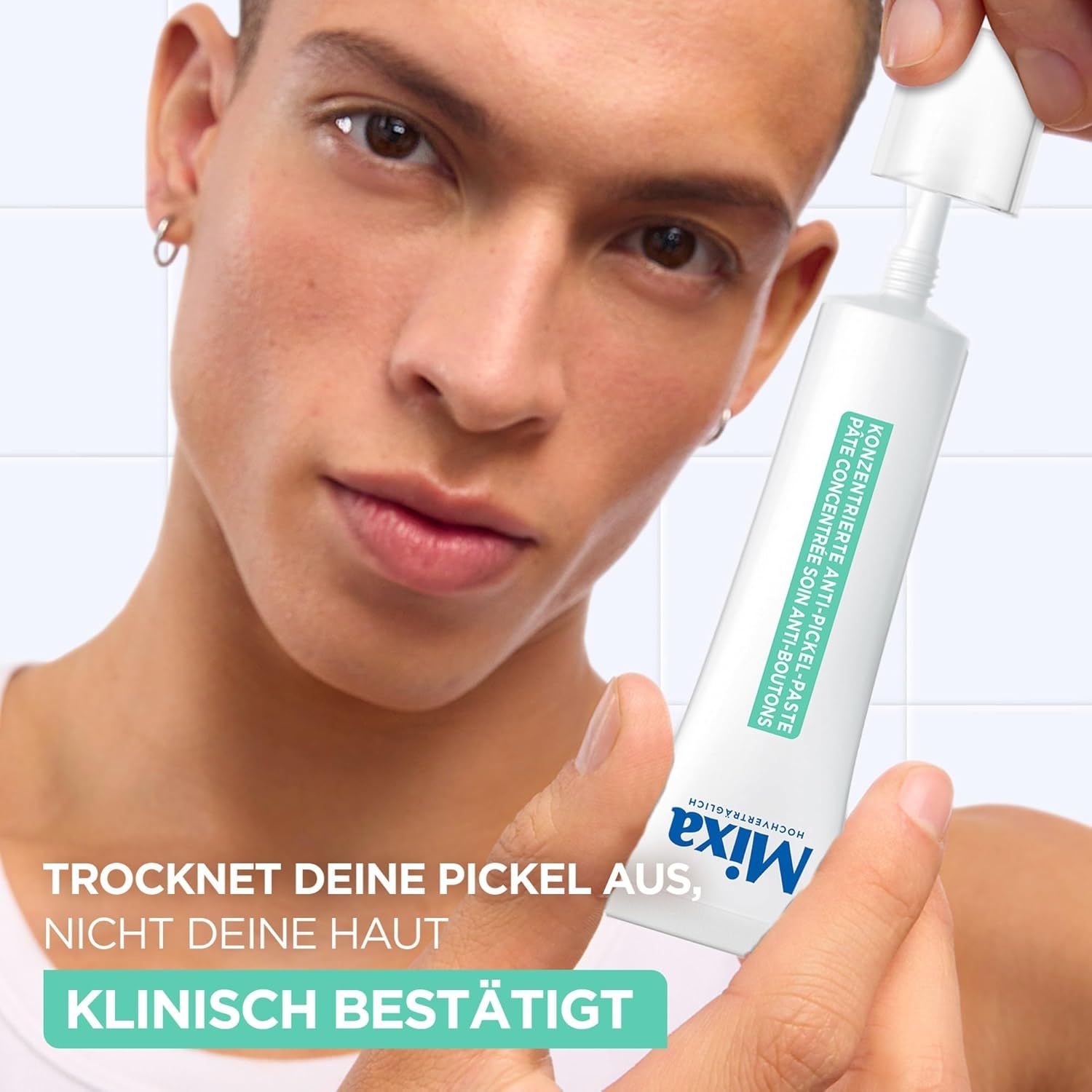 Weiße Tube mit Mixa-Logo und Text. Konzentrierte Anti-Pickel-Paste. Mann hält Tube und Kappe.