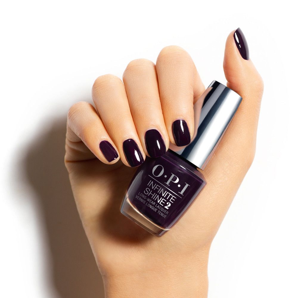Hand mit lackierten Nägeln und Nagellackflasche. Flasche mit silbernem Deckel, Produktname OPI Infinite Shine 2.