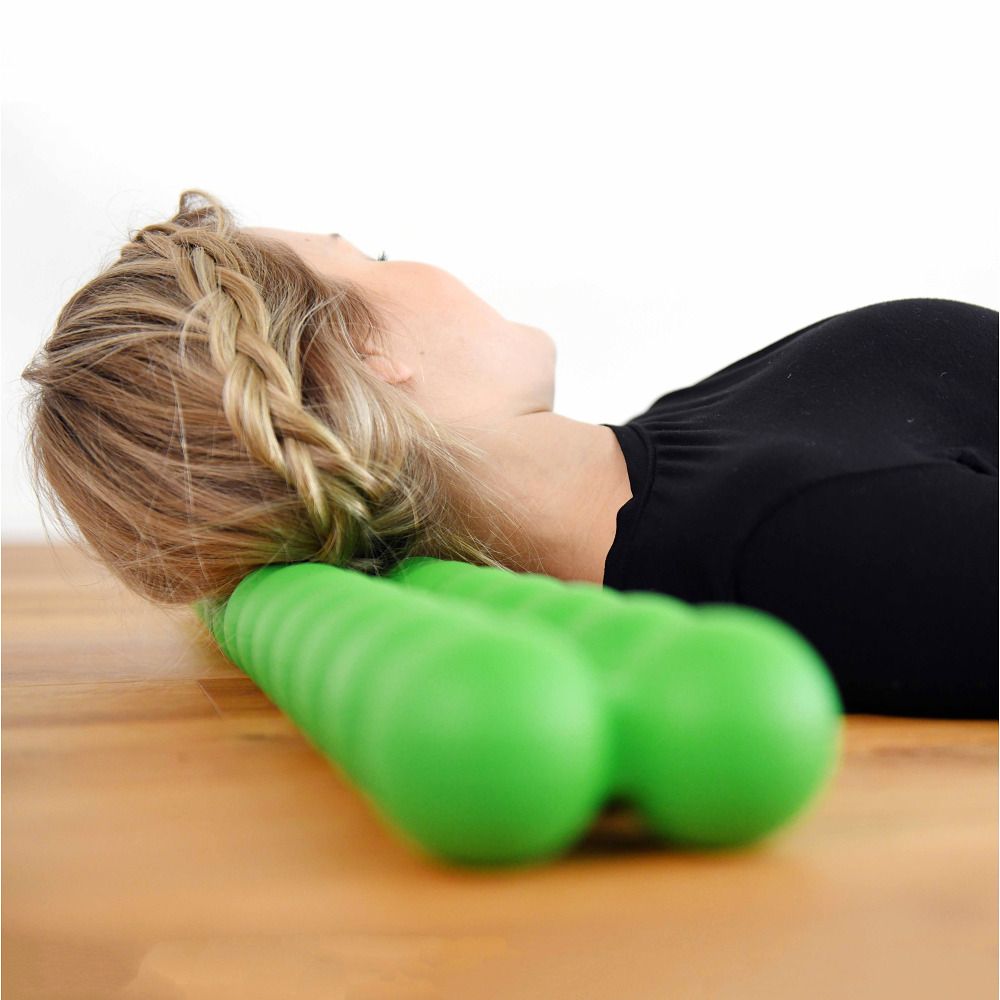 Eine Frau liegt mit dem Kopf auf einem grünen Spinefitter-Rückentrainer. Der Hintergrund ist hell und holzig.