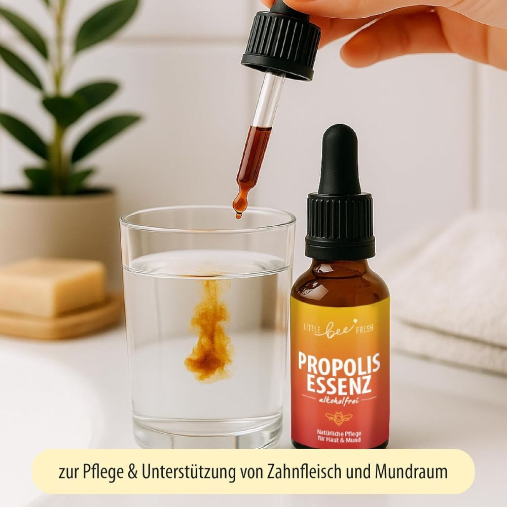 Tropfflasche neben einem Glas Wasser. Flüssigkeit tropft ins Wasser. Auf dem Etikett steht 'Propolis Essenz'.