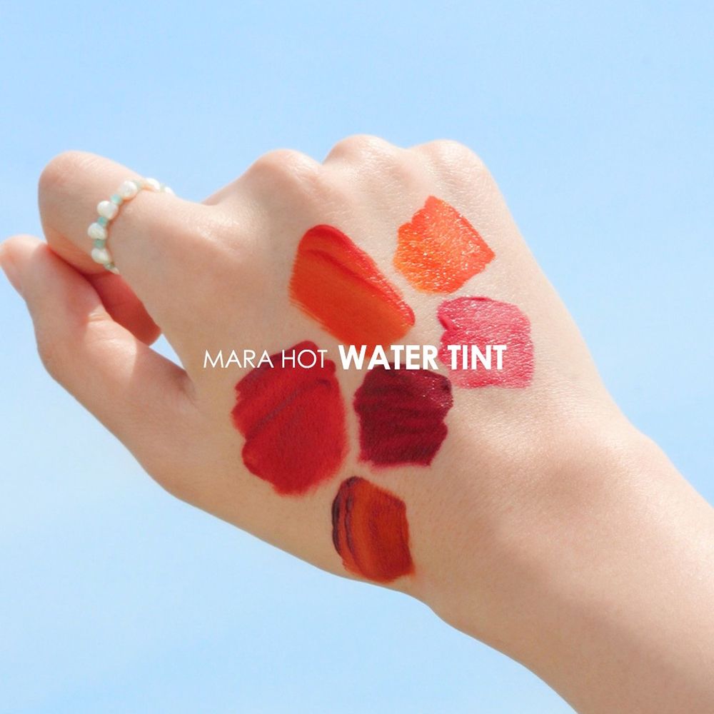 Hand mit Lip Tint-Farbmustern. Verschiedene Rottöne.