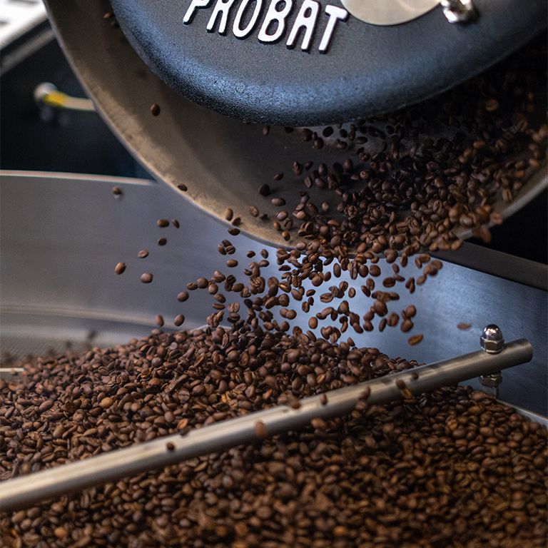 Kaffeebohnen fallen aus einer PROBAT-Röstmaschine. Maschine ist schwarz.