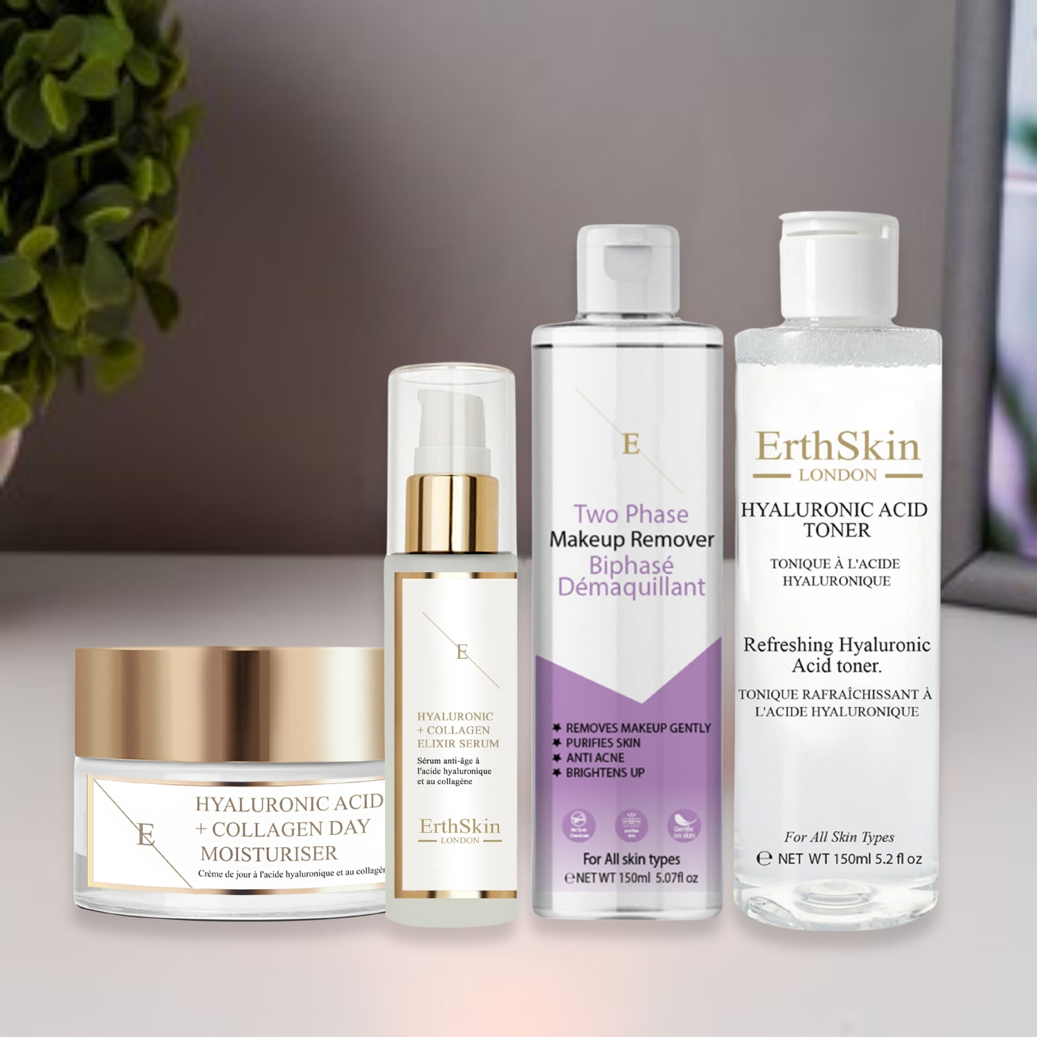 Vier Kosmetikprodukte auf einer Oberfläche. Tagescreme, Serum, Make-up-Entferner und Toner. Weiße Etiketten mit Text und Goldakzenten.