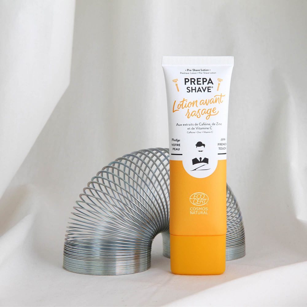 Weiße Tube mit gelbem Boden. Aufschrift: PREPA SHAVE Lotion avant rasage. Logo: Mann mit Bart. COSMOS NATURAL-Zertifizierung.