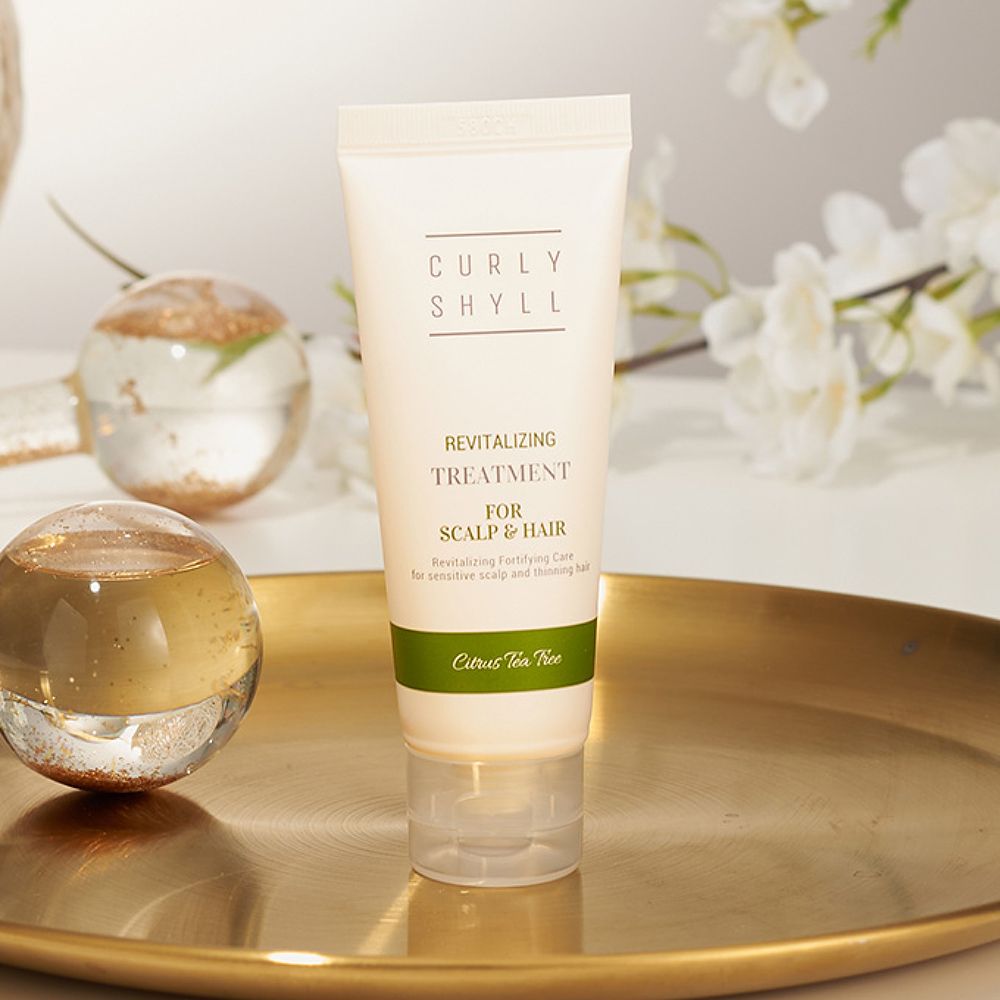 Tube auf Tablett. Produktname und Text sichtbar. Grüner Streifen mit "Citrus Tea Tree". Dekoration im Hintergrund.